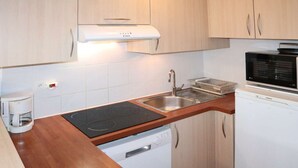 A compact kitchen with a built-in stove, a microwave, a dishwasher, and a coffee maker. - Spacious studio 6 ppl, ski-in/ski-out, Free Wifi (Les Orres)