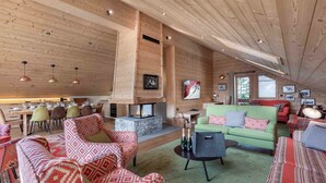 A spacious living area with a stone fireplace, wooden ceiling, and a dining area with a wooden table and chairs.
