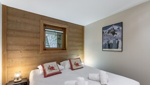 Habitación de hotel con cabecera de madera, ventana con vistas a un paisaje nevado y un cuadro en la pared.