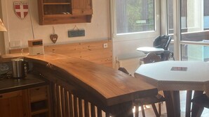 Une cuisine avec des meubles de rangement en bois, un plan de travail en bois et une fenêtre équipée de stores.