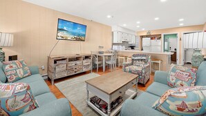 A cozy living room with a TV, a dining area, and a kitchen. - Oceanside Three Bedroom Condo Steps From the Beach (Ocean City)