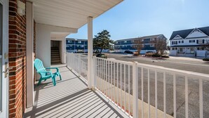A covered porch with a view of a street and other buildings. - Oceanside Three Bedroom Condo Steps From the Beach (Ocean City)