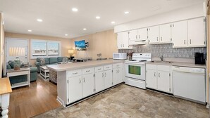 A modern kitchen with white cabinets, a central island, and a built-in oven. - Oceanside Three Bedroom Condo Steps From the Beach (Ocean City)