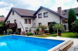 Une maison à deux étages avec une piscine en premier plan.