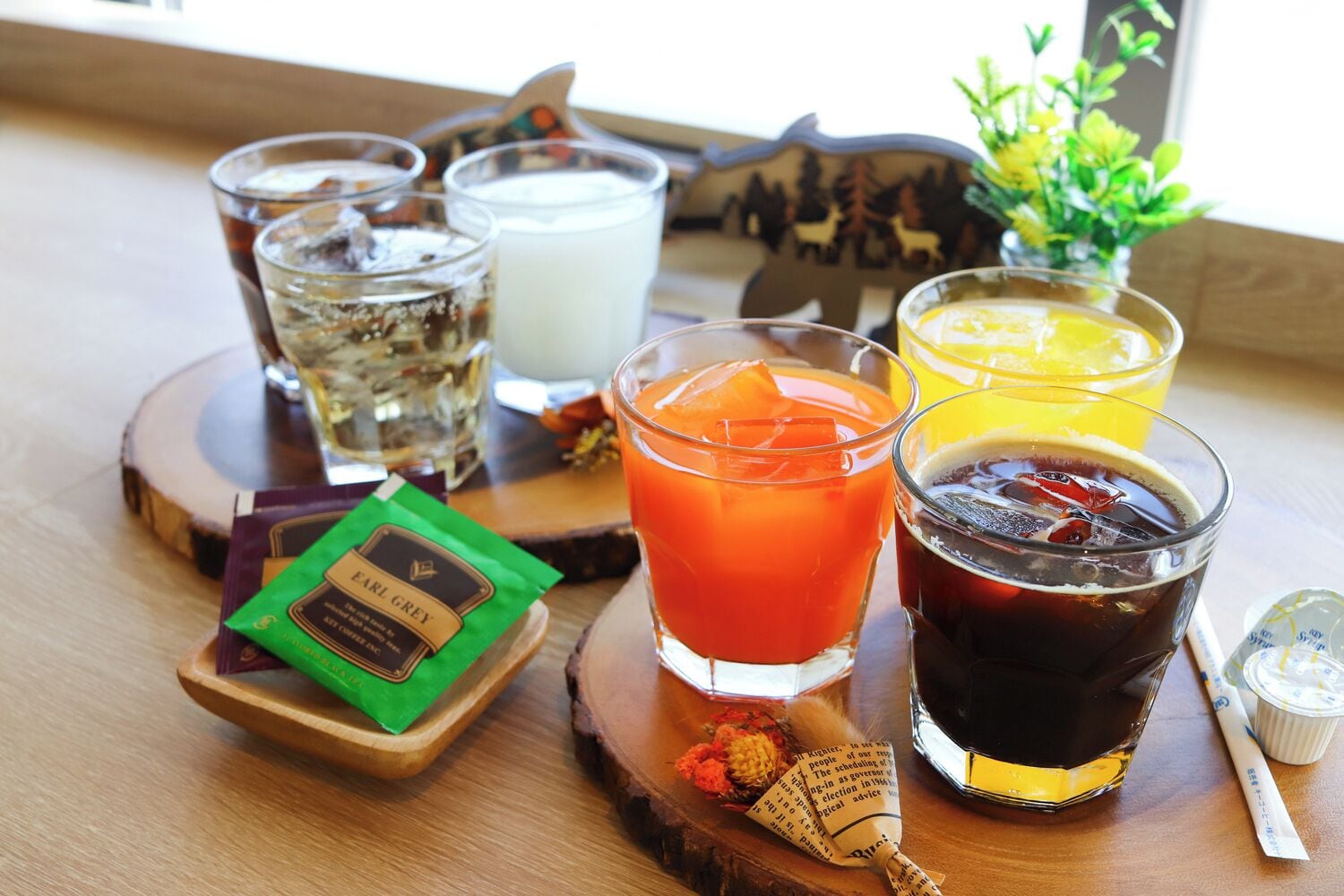 A wooden table with various drinks, a candle, and a packet of Earl Grey tea.