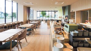 A modern dining area with tables and chairs, a buffet counter, and large windows offering a view of the street.