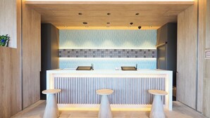 A reception area with a modern design, featuring a counter with two stools and a patterned backsplash.