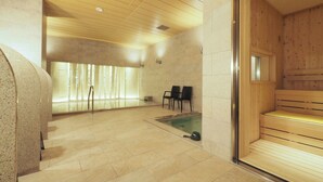 A sauna room with wooden benches and a small pool.