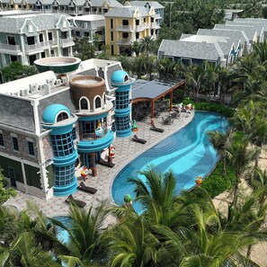 A resort with a large swimming pool surrounded by palm trees and a covered outdoor area with lounge chairs. - Wonderland Royal Mansions Ho Tram (Ho Chi Minh Municipality)