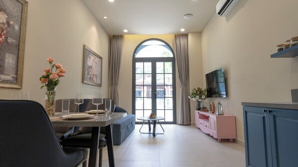 A dining area with a table set for four, a vase of flowers, and a painting on the wall. - Wonderland Royal Mansions Ho Tram (Ho Chi Minh Municipality)