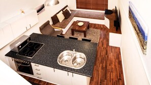 A compact kitchen with a double sink, a stove, and a dining area with a small table and chairs. - Razorback 10 - Jindabyne (Jindabyne)