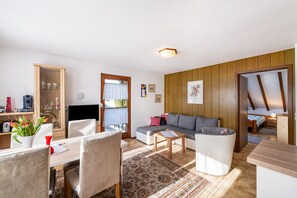 A cozy living room with a sofa, a dining table, and a TV. - Apartment '4' with Shared Garden, Balcony and Wi-Fi (Endingen am Kaiserstuhl)