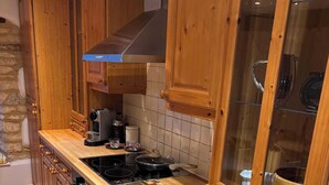 A kitchen with wooden cabinets, a stove, and a coffee maker.