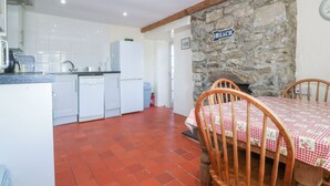 A kitchen with white cabinets, a refrigerator, and a stone wall with a 'BEACH' sign.
