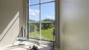 A room with a large window, a small table with a decorative item, and a window sill with seashells.