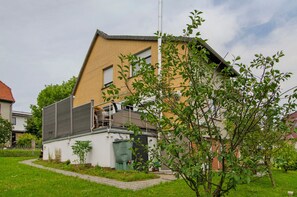 A residential building with a sloped roof, a visible chimney, and a small garden area with a pathway. - Apartment 'Harzblick am Waldesrand' with Mountain View, Private Terrace & Sauna (Hahausen)
