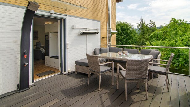 An outdoor deck with a dining set and a sliding glass door leading to an interior room. - Apartment 'Harzblick Am Waldesrand' with Mountain View, Private Terrace (and Sauna) (Hahausen)