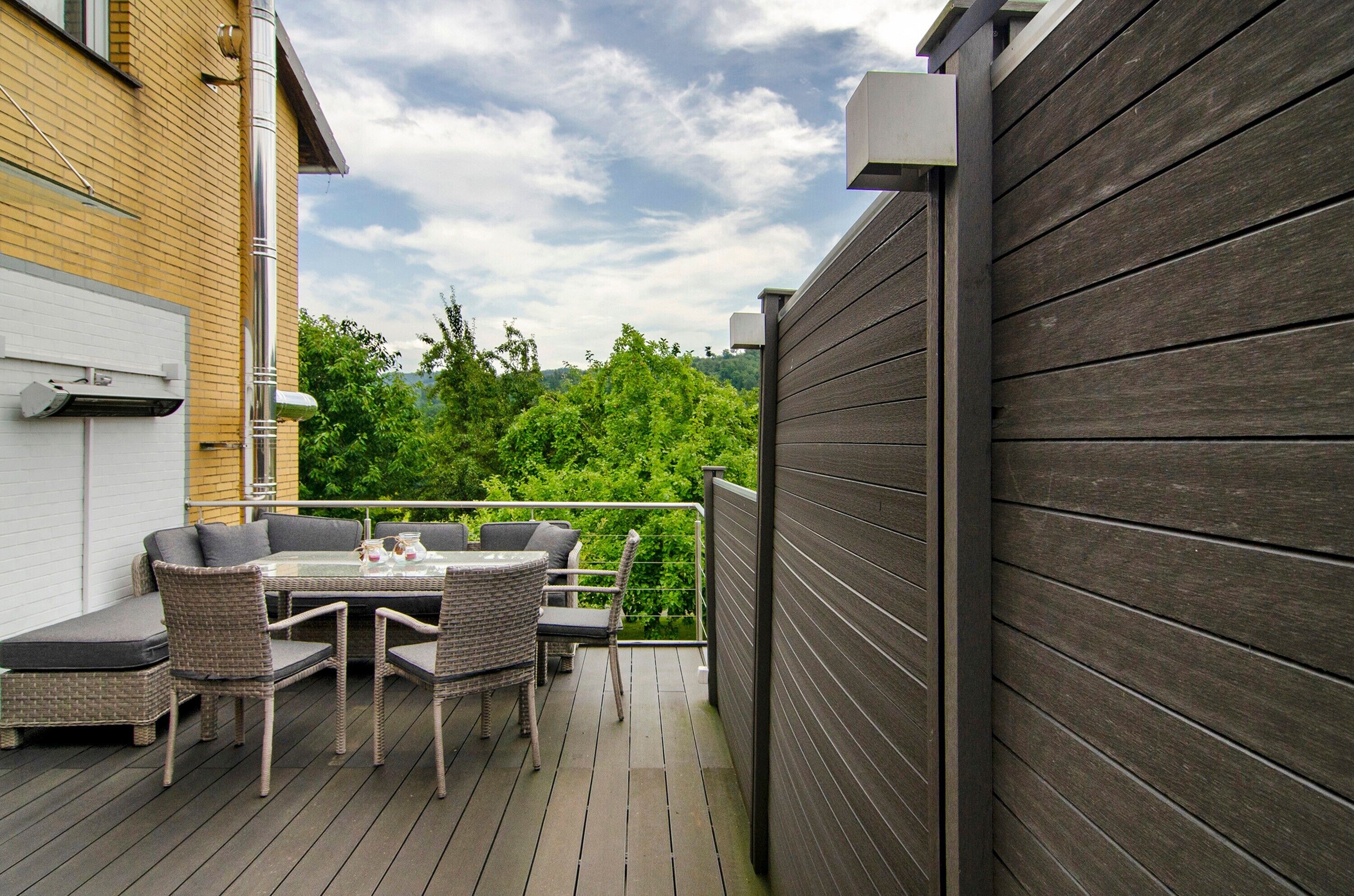 A deck with outdoor furniture, a white garage door, and a wooden fence.