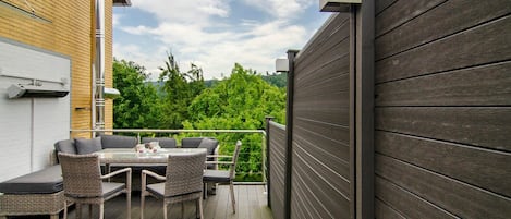 A deck with outdoor furniture, a white garage door, and a wooden fence.
