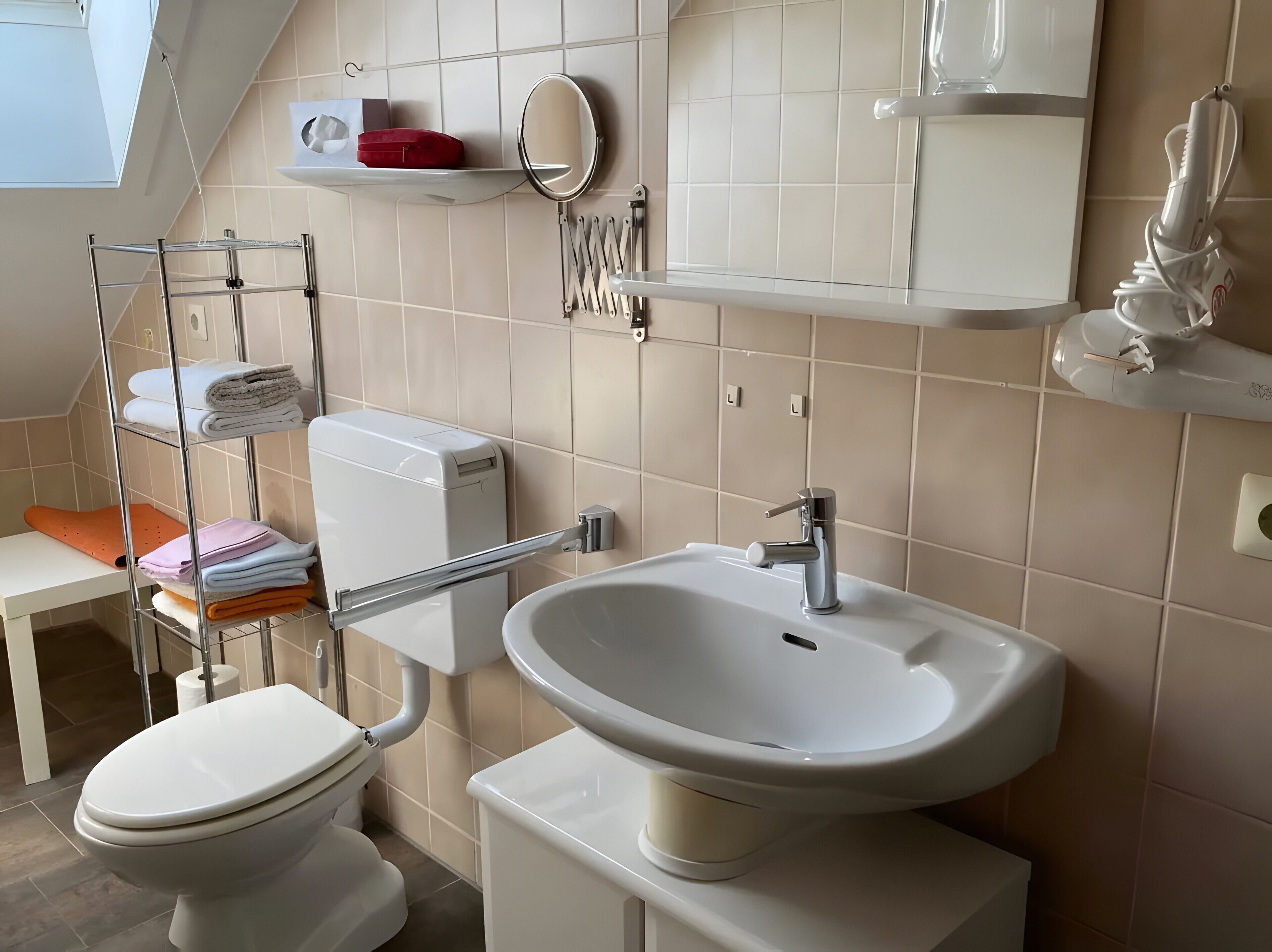 A modern bathroom with a toilet, sink, towel rack, and a mirror.