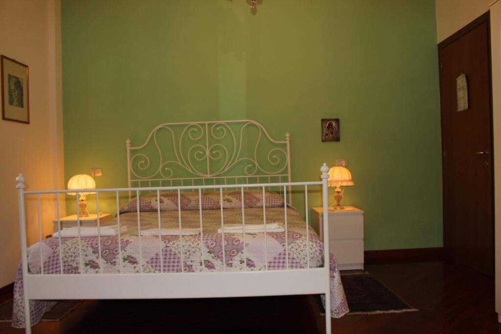 A bedroom with a white metal bed frame, green walls, and two bedside lamps.