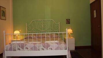 A bedroom with a white metal bed frame, green walls, and two bedside lamps.