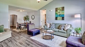 A living room with a dining area, a ceiling fan, a painting, and a floor lamp.