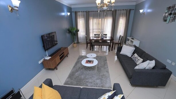 Ein modernes Wohnzimmer mit Sofa, Couchtisch, Fernseher und Essbereich.