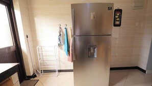Eine Küche mit einem Edelstahlkühlschrank, einem weißen Wäscheständer und einer gefliesten Spritzschutzwand.
