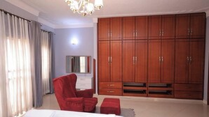 Ein Schlafzimmer mit einem großen Bett, einem roten Sessel, einem Holzschrank und einem Spiegel.