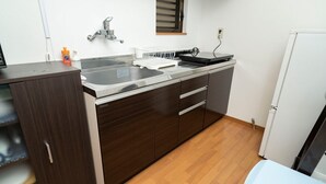 Une cuisine de taille réduite, dotée d’un évier en acier inoxydable, d’un réfrigérateur blanc et d’un meuble en bois.