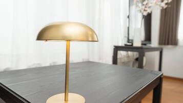 A modern table lamp with a gold base and a dome-shaped shade, placed on a dark wooden table.