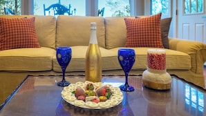 Ein Zimmer mit einer Couch, einem Tisch mit einer Flasche, Gläsern und einer Schokoladentafel.