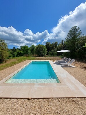 Une piscine rectangulaire à l’eau d’un bleu limpide, bordée de galets.