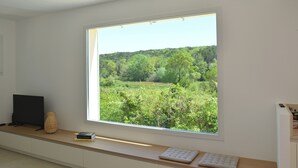 Ein Zimmer mit großem Fenster und Blick auf eine grüne Landschaft.