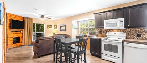 A modern kitchen with dark wooden cabinets, a white microwave, and a built-in oven.