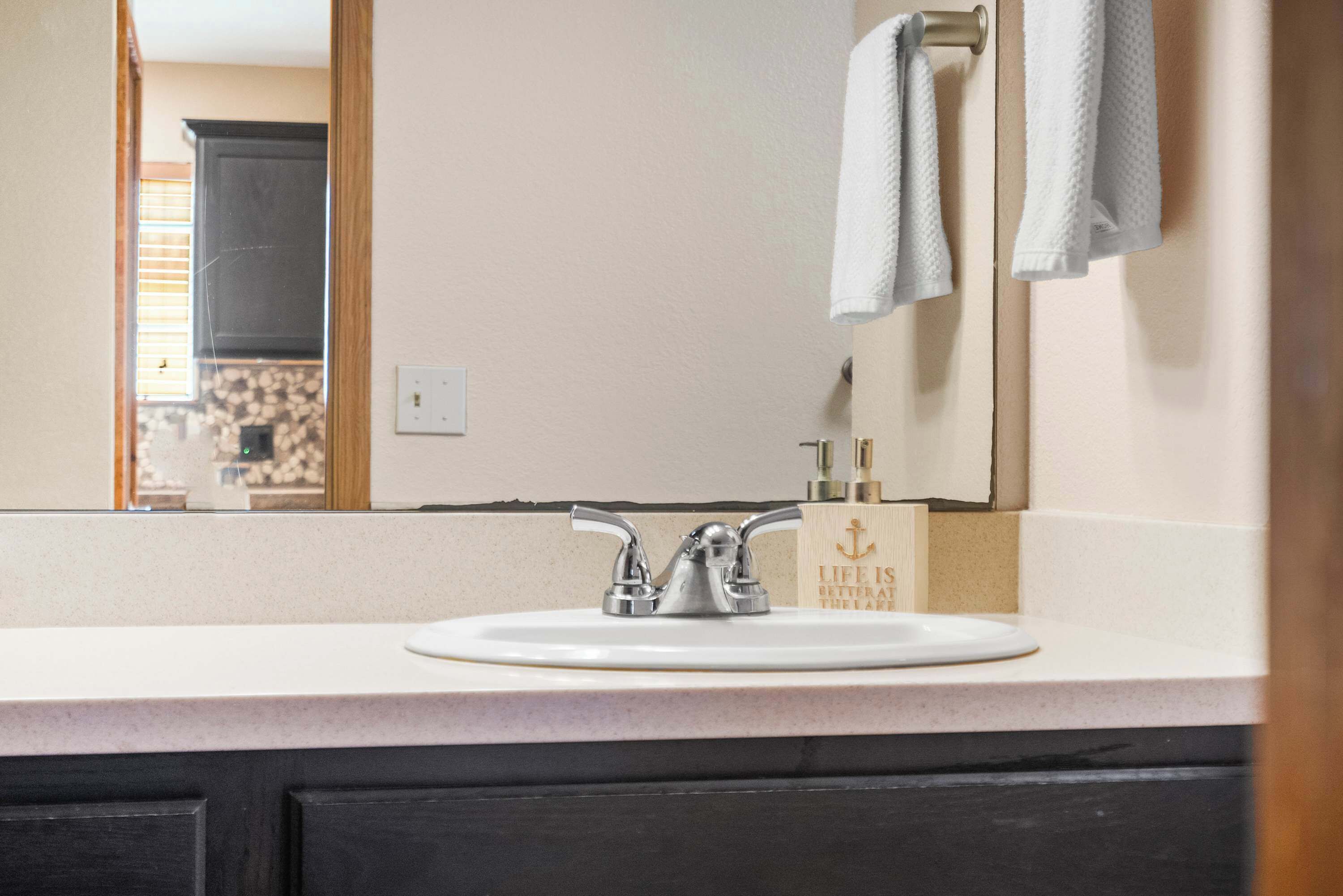 A bathroom with a white sink, a mirror, and a towel rack.