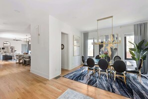 Een moderne eetruimte met een glazen tafel, zwarte stoelen en een tapijt met een zebraprint.