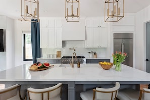 A modern kitchen with white cabinets, a large island with a sink, and a stainless steel refrigerator. - Cuppa Teal (Atlanta)