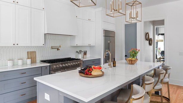 A modern kitchen with white cabinets, a large island, and bar stools.