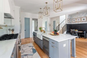 Een moderne keuken met een centraal eiland, inbouwapparatuur en hanglampen.
