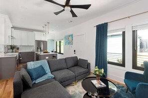 A modern living room with a grey sofa, a coffee table, and a ceiling fan. - Blue Burrow (Atlanta)