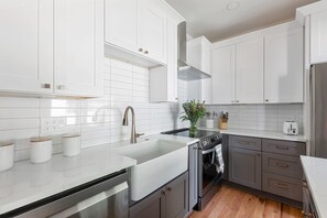 A modern kitchen with white cabinets, a stainless steel sink, and a built-in oven. - Blue Burrow (Atlanta)