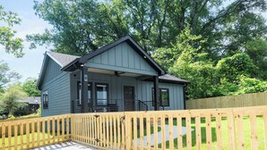 A two-story house with a covered porch and a wooden fence. - Blue Burrow (Atlanta)