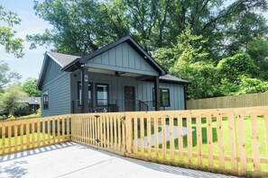 A two-story house with a covered porch and a wooden fence.