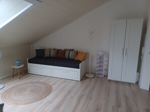 Une chambre avec un lit en mezzanine, une petite table de chevet, une lampe sur pied, une armoire et un tapis tissé.