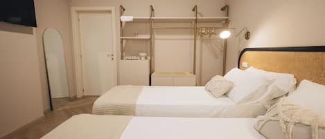 A bedroom with two beds, a wardrobe, a mirror, and a bedside table.