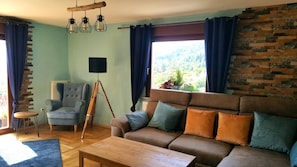 A living room with a sofa, armchair, and a tripod floor lamp.
