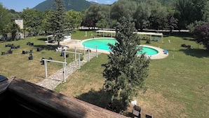 Ein Poolbereich mit freiem Blick auf die umliegende Landschaft, einschließlich Bäume und Berge.