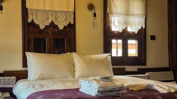 A room with a bed, a window with lace curtains, and a wooden door.